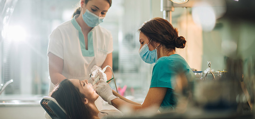 Two dental assistants working on a patient